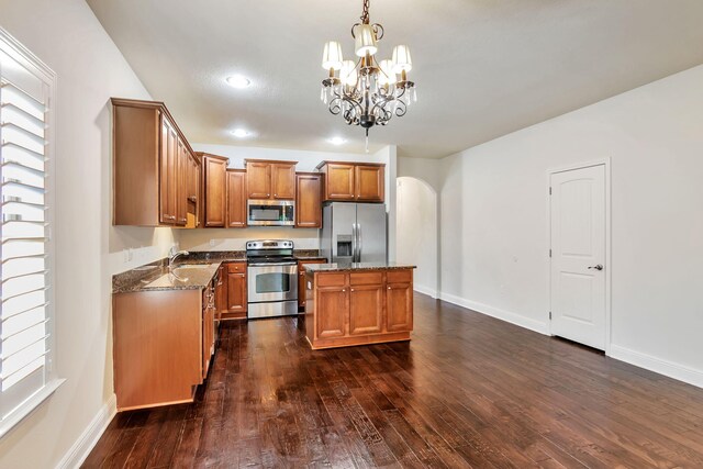256 Cocobolo Dr, Santa Rosa Beach, FL 32459 - kitchen with arched walkways, dark stone countertops, appliances with stainless steel finishes, and an inviting chandelier