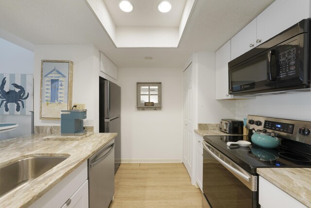 9815 W US Highway 98 Unit 215, Miramar Beach, FL 32550 - kitchen featuring white cabinets, a raised ceiling, appliances with stainless steel finishes, light stone countertops, and light wood-style flooring