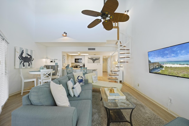 9815 W US Highway 98 Unit 215, Miramar Beach, FL 32550 - living room featuring stairway, a high ceiling, visible vents, ceiling fan, and light wood finished floors