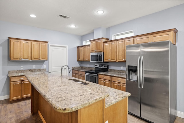 8393 New Orleans Ct, Navarre, FL 32566 - kitchen with appliances with stainless steel finishes, a sink, a center island with sink, light stone counters, and baseboards