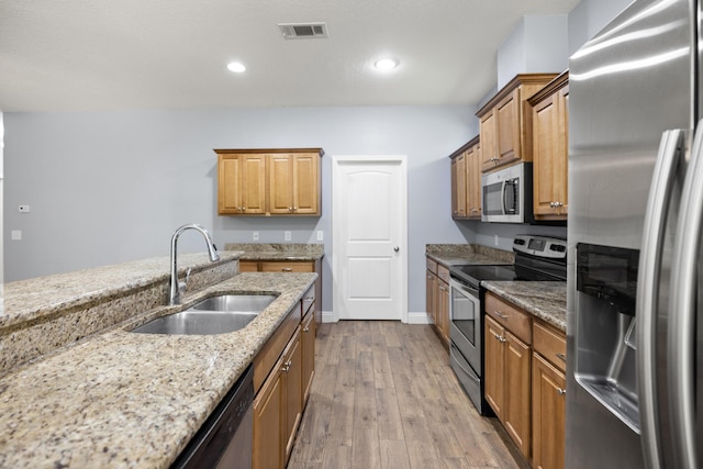 8393 New Orleans Ct, Navarre, FL 32566 - kitchen featuring stainless steel appliances, a sink, wood finished floors, light stone countertops, and brown cabinetry