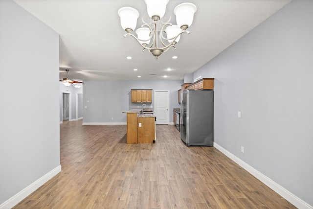 8393 New Orleans Ct, Navarre, FL 32566 - kitchen with freestanding refrigerator, open floor plan, brown cabinetry, a chandelier, and light wood-style flooring