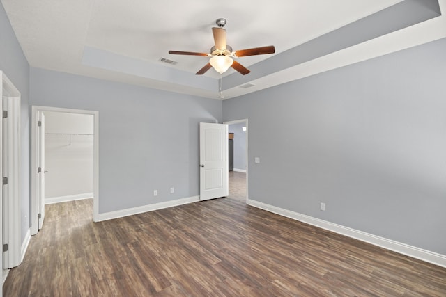 8393 New Orleans Ct, Navarre, FL 32566 - unfurnished bedroom featuring a raised ceiling, dark wood-type flooring, a spacious closet, baseboards, and ceiling fan