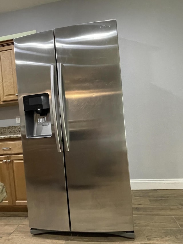 8393 New Orleans Ct, Navarre, FL 32566 - detailed view of stainless steel fridge, baseboards, light wood-style floors, and light stone counters