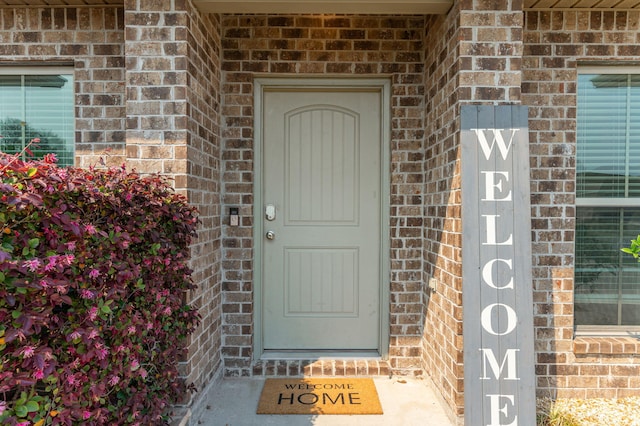view of exterior entry featuring brick siding