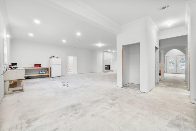 680 Mallet Bayou Rd, Freeport, FL 32439 - below grade area with crown molding, freestanding refrigerator, a large fireplace, visible vents, and arched walkways