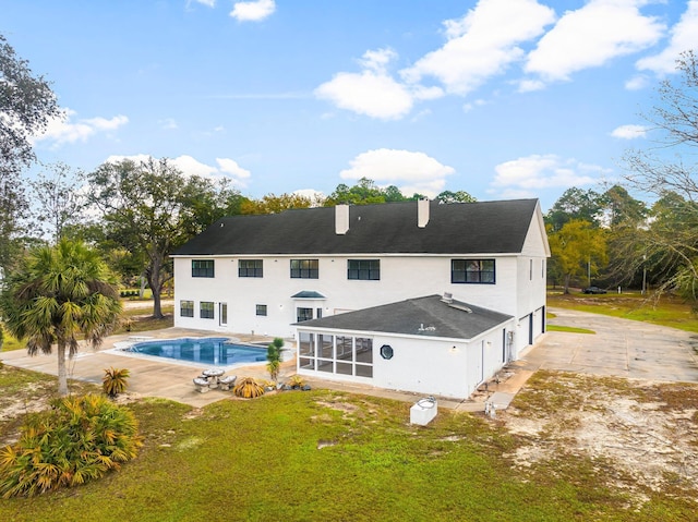 680 Mallet Bayou Rd, Freeport, FL 32439 - back of property featuring a sunroom, an outdoor pool, a patio, a garage, and stucco siding