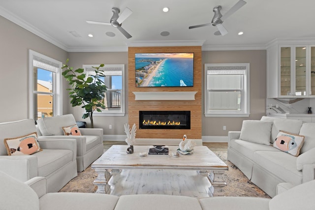 living area with a fireplace, ceiling fan, wood finished floors, and ornamental molding