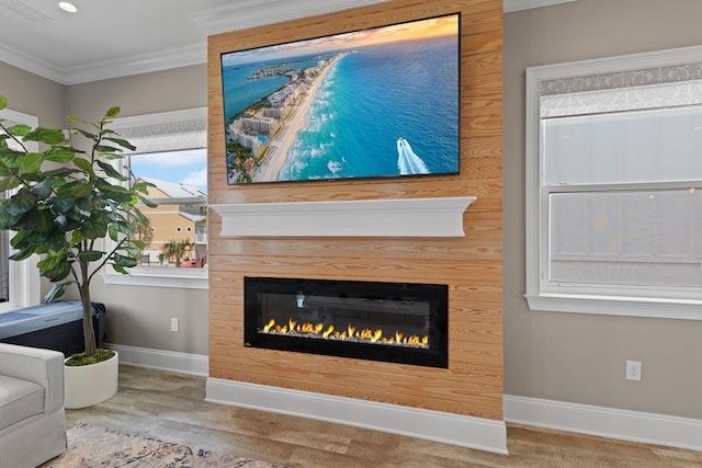 room details featuring visible vents, baseboards, ornamental molding, wood finished floors, and a glass covered fireplace