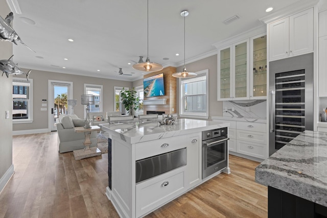 kitchen with white cabinets, a warming drawer, wine cooler, and stainless steel oven