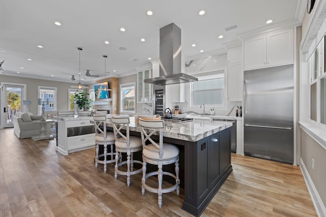 kitchen with a center island, island range hood, white cabinetry, and built in refrigerator