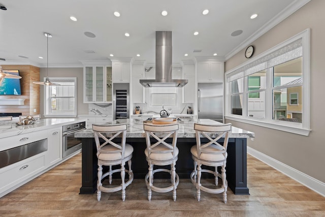 kitchen featuring island range hood, white cabinets, a kitchen island with sink, and stainless steel appliances
