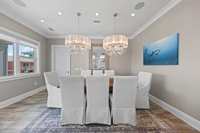 dining area with visible vents, wood finished floors, ornamental molding, and an inviting chandelier