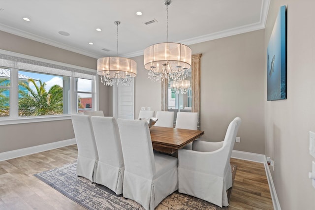 dining area with baseboards, wood finished floors, ornamental molding, and an inviting chandelier