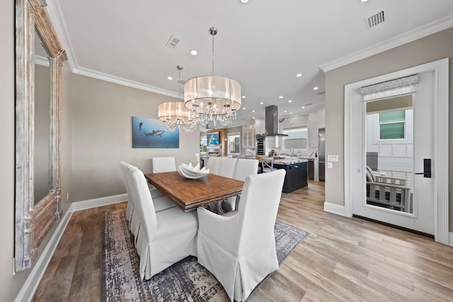 dining room featuring a notable chandelier, ornamental molding, visible vents, and light wood-type flooring