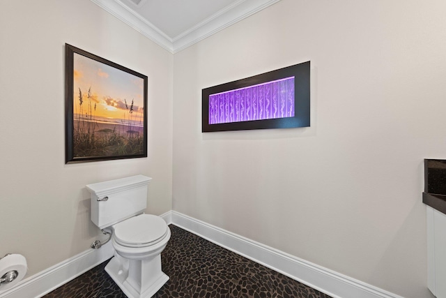 half bathroom with toilet, crown molding, and baseboards