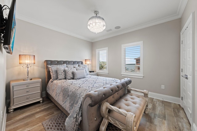bedroom with baseboards, ornamental molding, wood finished floors, and an inviting chandelier