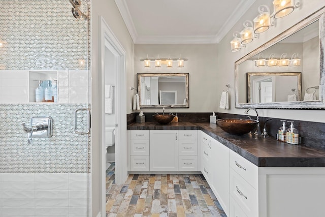 bathroom featuring vanity, toilet, crown molding, and a shower stall