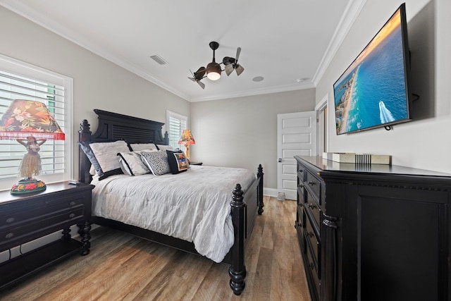 bedroom with light wood-type flooring, ornamental molding, baseboards, visible vents, and a ceiling fan