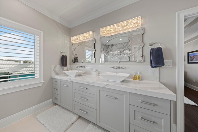 full bathroom with double vanity, a sink, ornamental molding, and baseboards