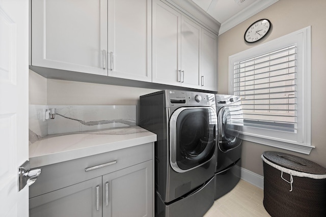 washroom with cabinet space, crown molding, washer and clothes dryer, and baseboards