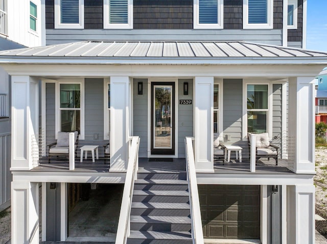 entrance to property with metal roof, a standing seam roof, a porch, and a garage