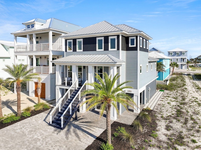 beach home featuring a porch, driveway, stairs, and metal roof