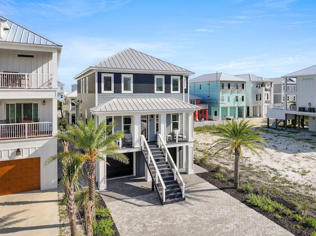 view of front of property featuring covered porch, a standing seam roof, stairway, metal roof, and decorative driveway
