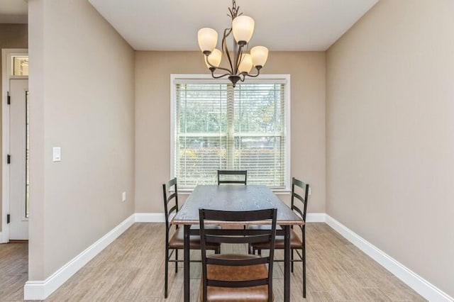 dining space with an inviting chandelier, light wood-style flooring, and baseboards