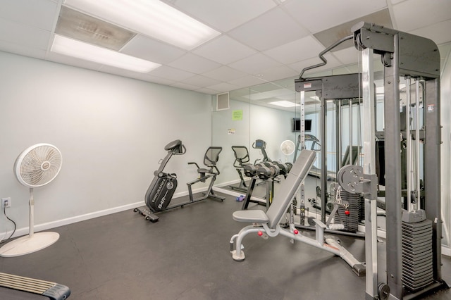 workout area featuring baseboards, visible vents, and a paneled ceiling
