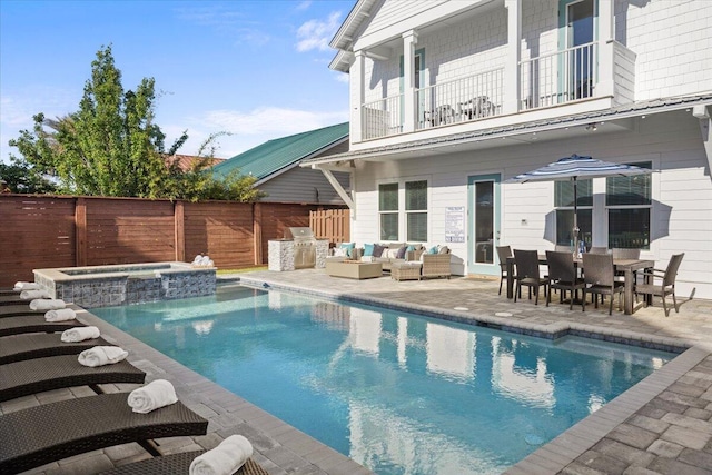 view of pool featuring a patio area, a pool with connected hot tub, fence, outdoor dining area, and an outdoor hangout area