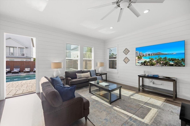 living area with wood walls, recessed lighting, a ceiling fan, and wood finished floors