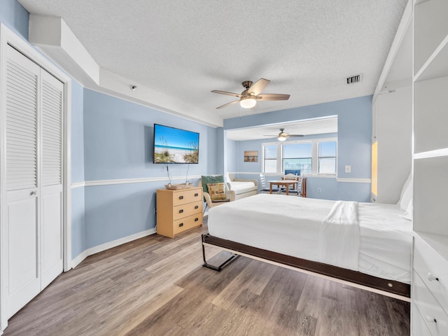 8730 Thomas Dr # 1203C, Panama City Beach, FL 32408 - bedroom with a textured ceiling, visible vents, baseboards, wood finished floors, and a ceiling fan