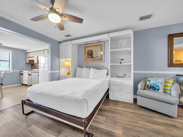 8730 Thomas Dr # 1203C, Panama City Beach, FL 32408 - bedroom with freestanding refrigerator, wood finished floors, a textured ceiling, and visible vents