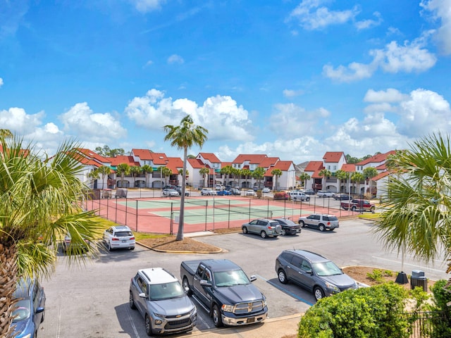8730 Thomas Dr # 1203C, Panama City Beach, FL 32408 - uncovered parking lot featuring a residential view, fence, and a tennis court