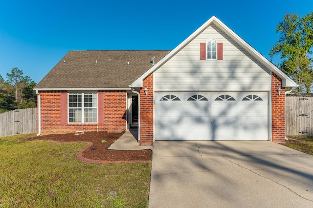 view of front facade with a front yard, roof with shingles, concrete driveway, fence, and brick siding