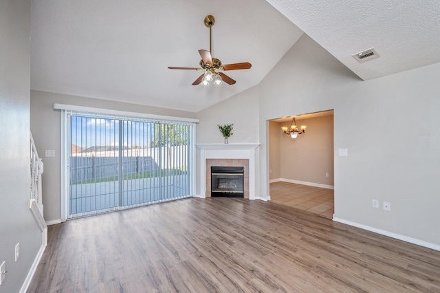 unfurnished living room featuring visible vents, baseboards, a fireplace, wood finished floors, and ceiling fan with notable chandelier