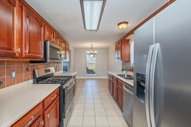 kitchen with light countertops, a sink, a notable chandelier, and appliances with stainless steel finishes