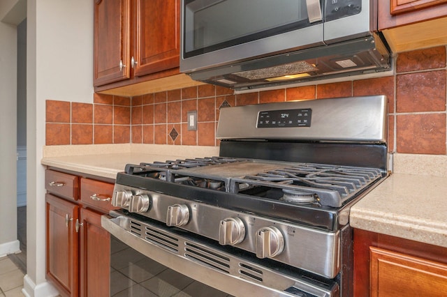 kitchen featuring light countertops, tasteful backsplash, appliances with stainless steel finishes, and brown cabinets