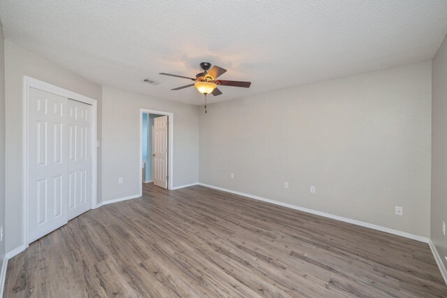 unfurnished bedroom with baseboards, visible vents, a closet, and wood finished floors