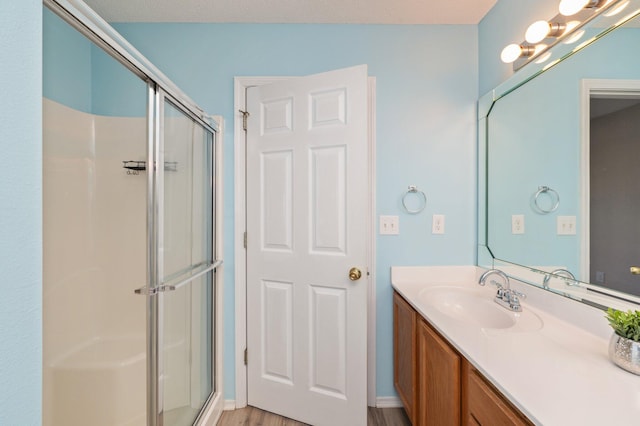 full bath featuring wood finished floors, a stall shower, and vanity
