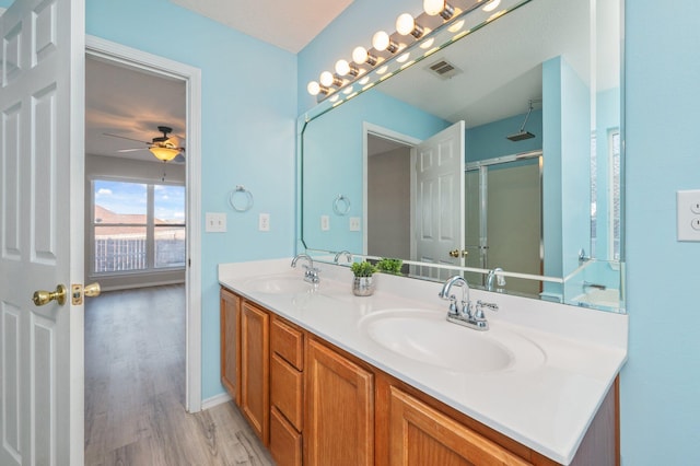 full bath with double vanity, visible vents, wood finished floors, and a sink