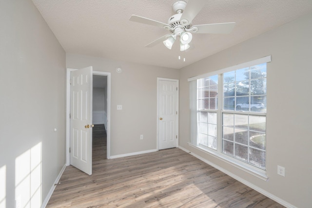 empty room with baseboards, a wealth of natural light, wood finished floors, and ceiling fan