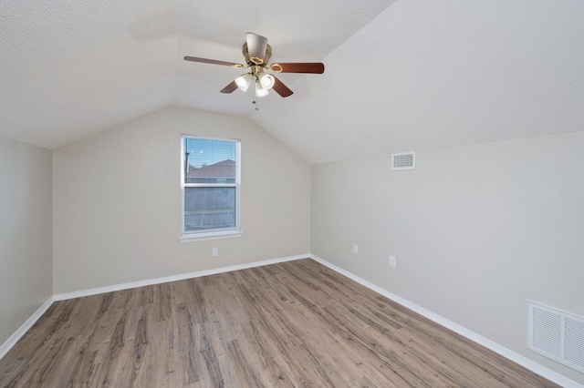 bonus room with wood finished floors, a textured ceiling, lofted ceiling, and visible vents