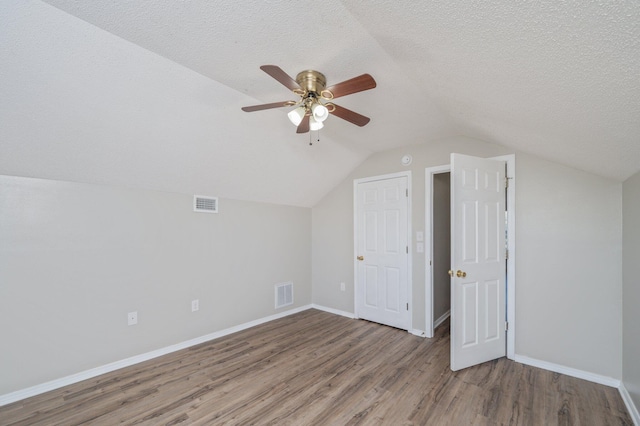 bonus room with lofted ceiling, a textured ceiling, visible vents, and wood finished floors
