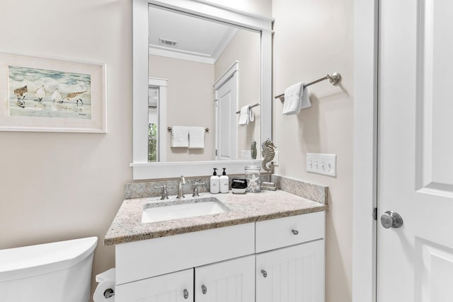 bathroom featuring visible vents, crown molding, toilet, and vanity