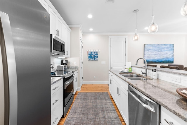 kitchen featuring ornamental molding, a sink, white cabinets, and appliances with stainless steel finishes