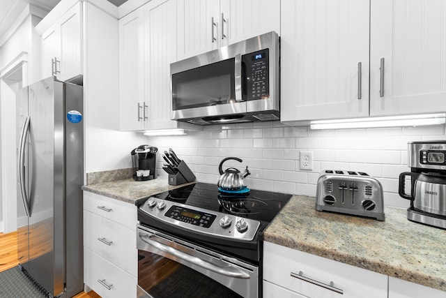 kitchen featuring backsplash, stainless steel appliances, white cabinetry, and light stone counters