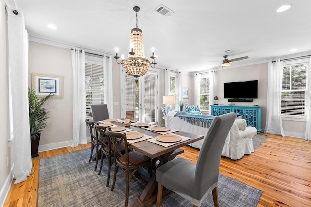 dining room featuring baseboards, visible vents, wood finished floors, and ceiling fan with notable chandelier