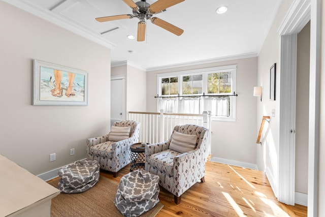 living area featuring baseboards, ornamental molding, wood finished floors, and a ceiling fan